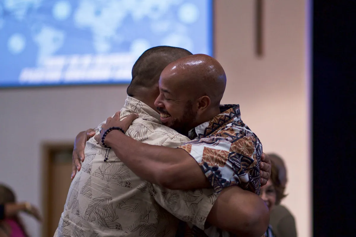 Two men greet each other with a hug at church.